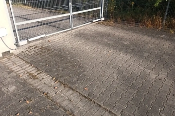 zabrudzona kostka brukowa przed myciem – osady i naloty przy bramie wjazdowej